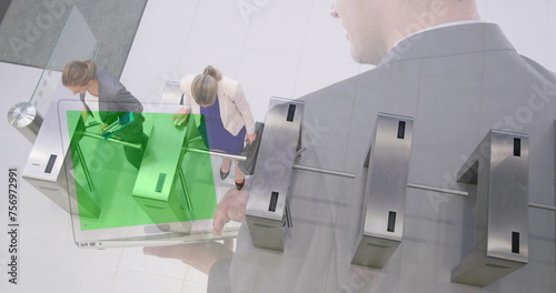 Image of businessman using laptop with green screen over women walking through turnstiles photo