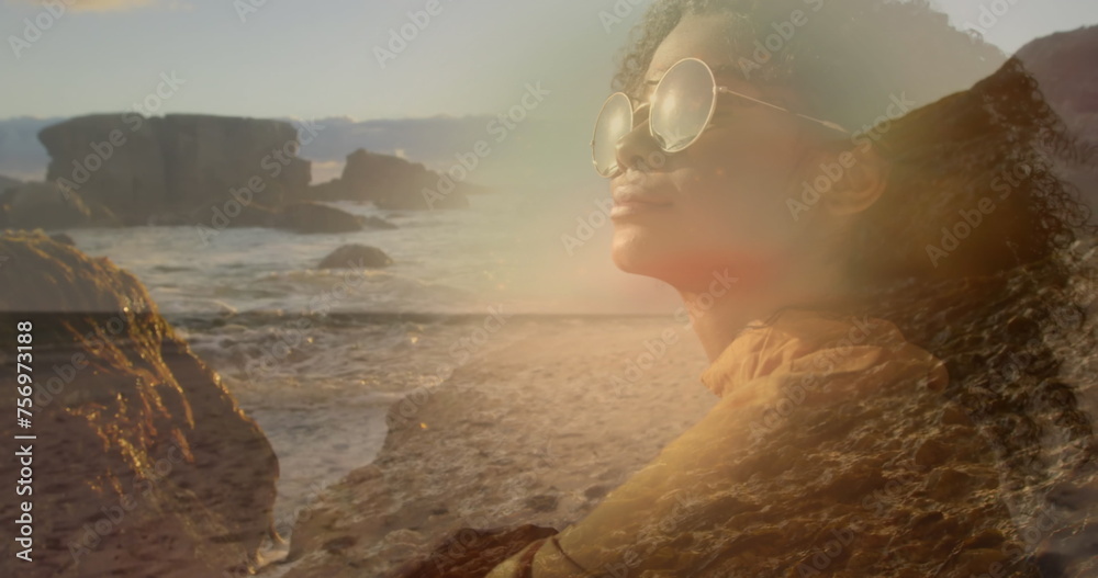 Fototapeta premium Image of african american woman in sunglasses over sunny landscape