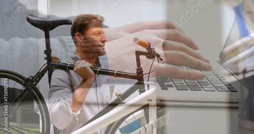 Image of hands using laptop over businessman climbing stairs carrying bike