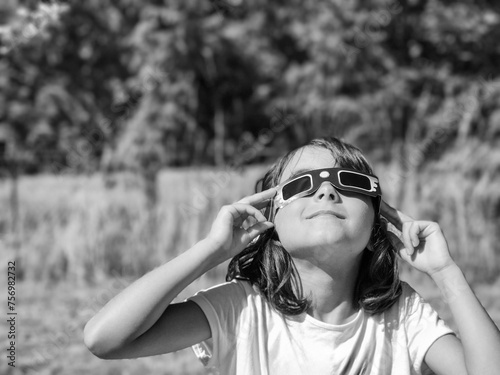 A young girl looking at the sun during a solar eclipse on a country park, family outdoor activity