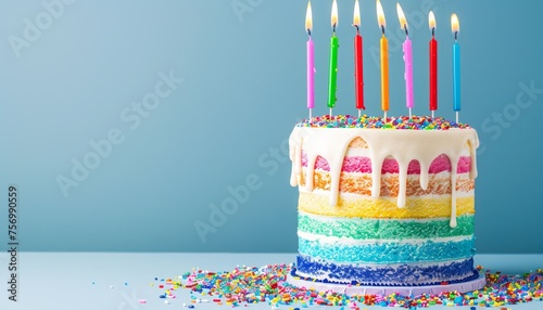 Colorful cake with rainbow candles blue background and copy space for a party
