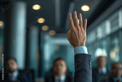 Close-up of a raised hand in a business conference, concept of volunteering, participation, and corporate engagement. © Sariyono
