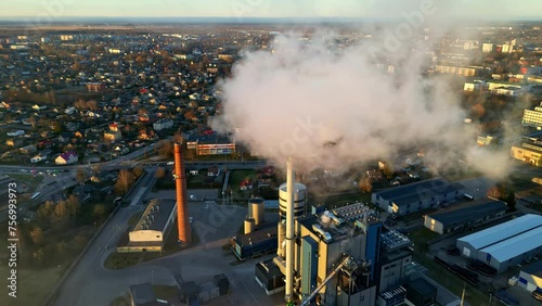 Smoking factory chimneys, polluting in a sunlit urban community - Aerial view photo