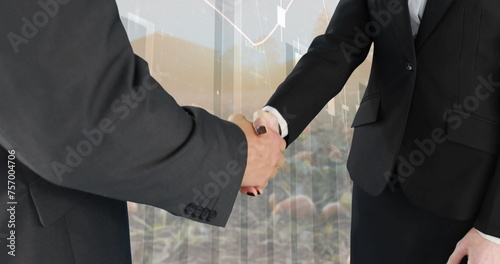 Handshake between business professionals over crop field with digital graphs.