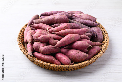 Organic raw sweet potatoes in basket on white table