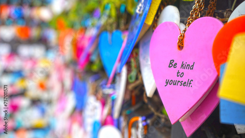Colorful hearts on the street hanging on wall with text message - Be kind to yourself. Self love and care concept. Inspirational and self motivational quotes. photo