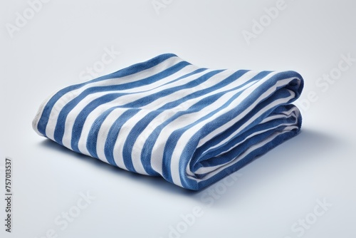 A folded beach towel with blue stripes is placed alone on a white background representing a decoration idea for a summer vacation resort © LimeSky