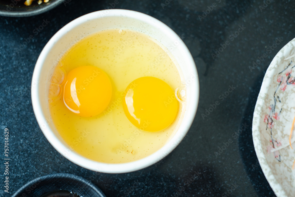 Two eggs in a small bowl. Egg Yolk contain protein, vitamins, minerals, omega 3 and other nutrients Two eggs in a small bowl. Egg Yolk contain protein, vitamins, minerals, omega 3 and other nutrients