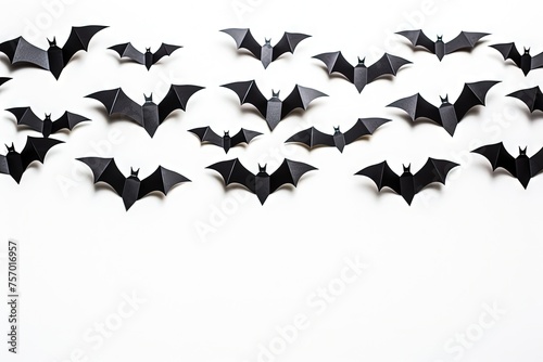 Black paper bats flying over a white background a Halloween decoration concept © LimeSky