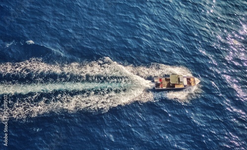 Top view of a fishing vessel going through
water living backwash in calm blue waters 