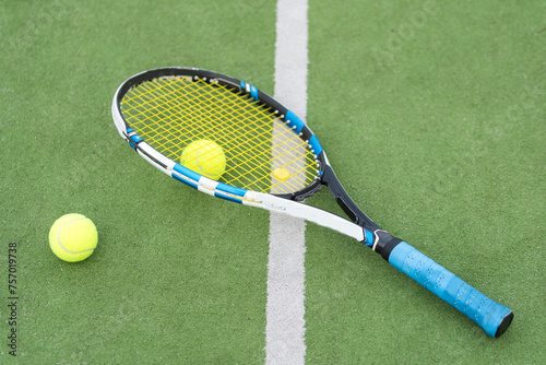 Tennis racket and tennis ball besides the net on outdoor tennis court. © Angelov