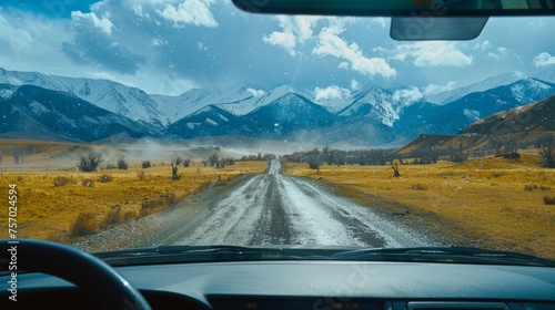An aerial view of the landscape through the windshield of a car going across a meadow to high rocky mountains in different seasons with varying weather. The “natural landscape” is viewed from inside photo