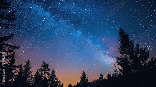 Starry night sky with nebula over silhouette of forest trees.