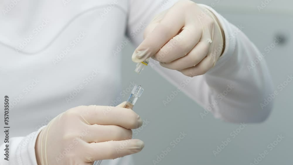 A cosmetologist or doctor prepares a syringe for injection. Preparing a needle for injection on a light background. A cosmetologist or doctor prepares a syringe for injection. Preparing a needle for injection on a light background.