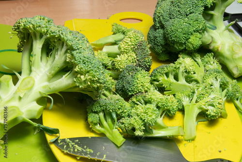 The broccoli in the kitchen on the cutting board, bright green in color, compact and fresh, is very healthy, nutritious, excellent for a fresh and tasty menu.