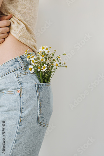 Young woman wuth chamomile flowers bouquet in jeans pocket