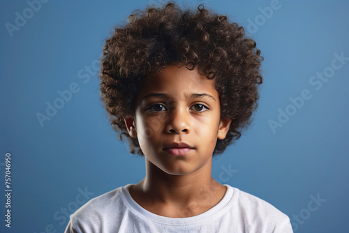 Pensive young boy with a natural hairstyle on a blue background