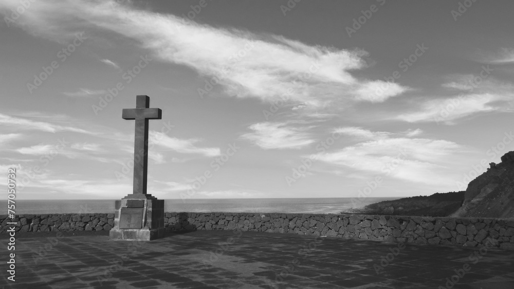 a grayscale shot of the cross of the ocean in the background - obrazy, fototapety, plakaty 