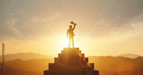 Silhouette of businessman holding a trophy on top staircase with light sunset. concept of a successful business or determination to lead the organization to success. photo