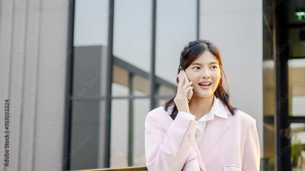 portrait of a young asian businesswoman walking in the city on the rooftop of her office building, smiling and speaking on mobile phone, with negotiation and professional discussion in city. portrait of a young asian businesswoman walking in the city on the rooftop of her office building, smiling and speaking on mobile phone, with negotiation and professional discussion in city.