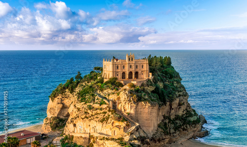 sea landscape of beautiful white temple or castle on a high cliff isle on a rock in crystal clear turquoise sea with waves and beautiful sunset or sunrise on background of seascape