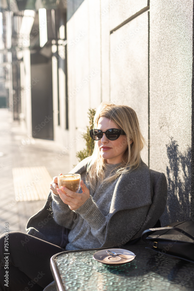 Young beautiful woman sitting in a cafe and drinking a cappuccino. Young beautiful woman sitting in a cafe and drinking a cappuccino.