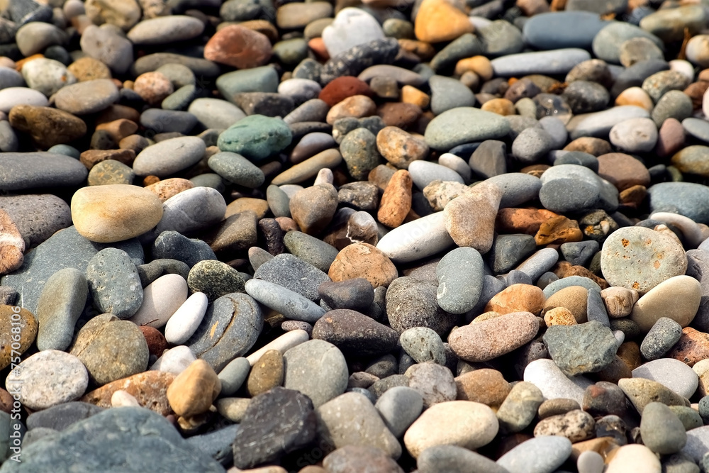 Pebble sea beach with stones of different size colors shimmer in sun in sunny weather. Beautiful stones surface on sea coast. Coastal texture, shoreline, coastline with smoothy rocks. Pebble sea beach with stones of different size colors shimmer in sun in sunny weather. Beautiful stones surface on sea coast. Coastal texture, shoreline, coastline with smoothy rocks.