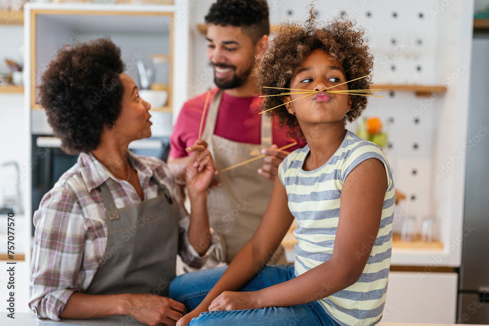 Happy smiling african american parents enjoy weekend play with child in kitchen. Family love concept