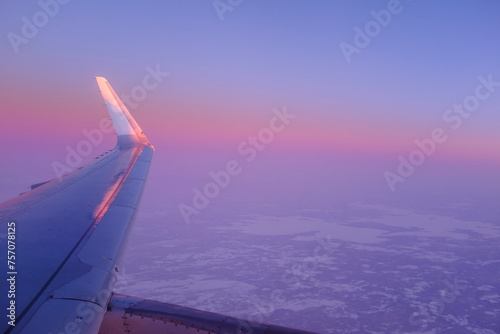 Airplane flying over a snowy landscape in Rovaniemi  Finland on a beautiful cloudy sunset sky with aircraft wing