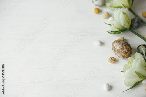 Happy Easter! Stylish easter eggs and tulips on rustic white table flat lay. Modern natural dye marble eggs and spring flowers. Easter festive border, space for text #757085919