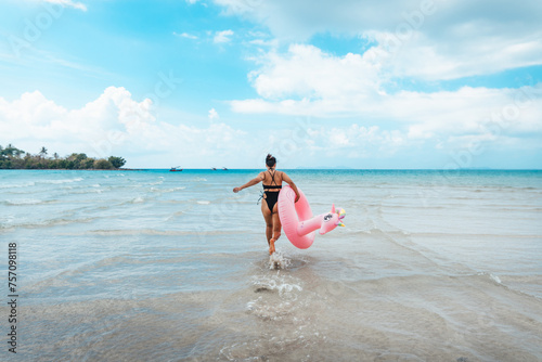 Summer travel  woman holding an inner tube  walking in the middle of the sea