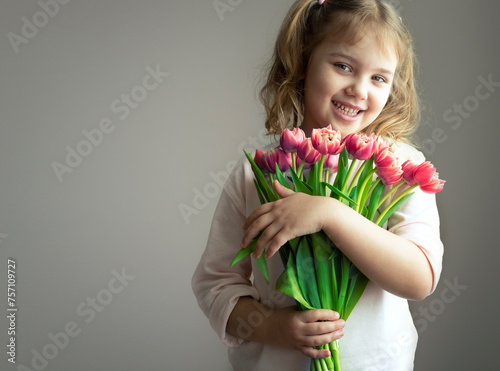 Beautiful caucasian child girl holding flowers bouquet.Little kid portrait empty copy space.Mother's day holiday.