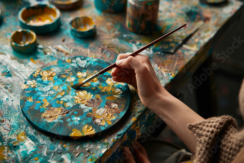Woman's hand of artist with brush painting floral yellow blue picture.