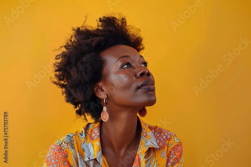 A woman with curly hair and a yellow shirt is looking up at the camera
