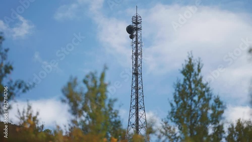A communication tower with antennae stands above the autumn forest. photo