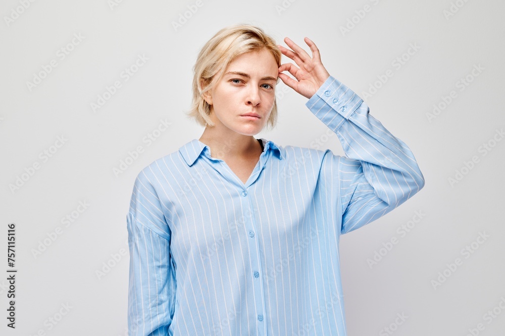 Woman in blue shirt with hand on forehead looking confused, forgetful, isolated on light background