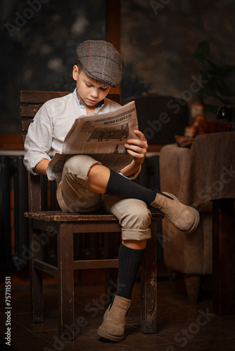 Focused boy reads newspaper, cap on, immersed in learning.