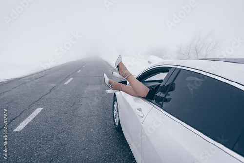 Принти на полотні Playful moment as a person's legs dangle out of a white car's window against a f