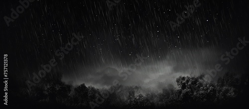 A monochromatic photograph capturing the eerie atmosphere of a stormy night with dark clouds looming over a natural landscape. The black forest is shrouded in a veil of mist under the midnight sky