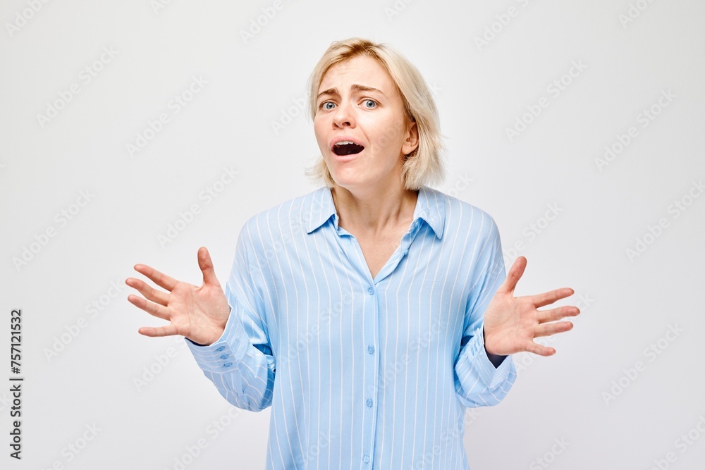 Woman expressing shock and confusion with hands raised against a white background. Woman expressing shock and confusion with hands raised against a white background.