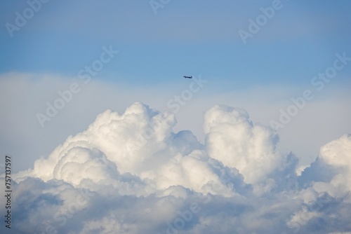 Gros nuages blancs et un avion dans un ciel turbulent  photo