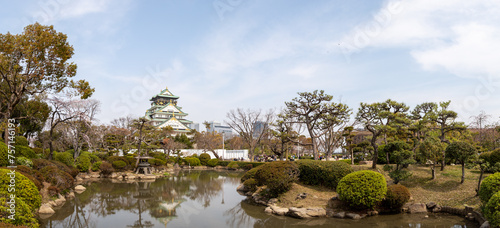 Osaka Castle, A beautiful park with a pond and a large building in the background