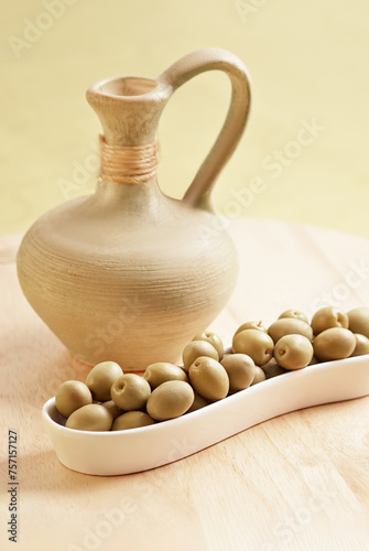 Olives in white playe with a jar on the wooden plate photo