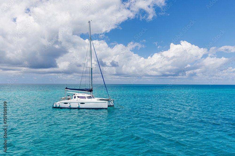 White sailing boat traveling in Maldives blue sea water on a bright sunny summer day in the middle of nowhere. Tropical sea and sailing boat. No sails up in calm sea waves. Freedom adventure tourism White sailing boat traveling in Maldives blue sea water on a bright sunny summer day in the middle of nowhere. Tropical sea and sailing boat. No sails up in calm sea waves. Freedom adventure tourism