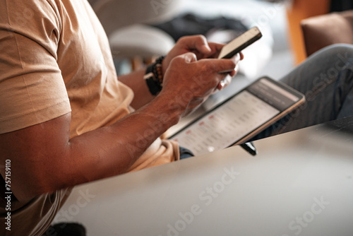 Close up of a young black man using mobile in living room and texting massages to colleague