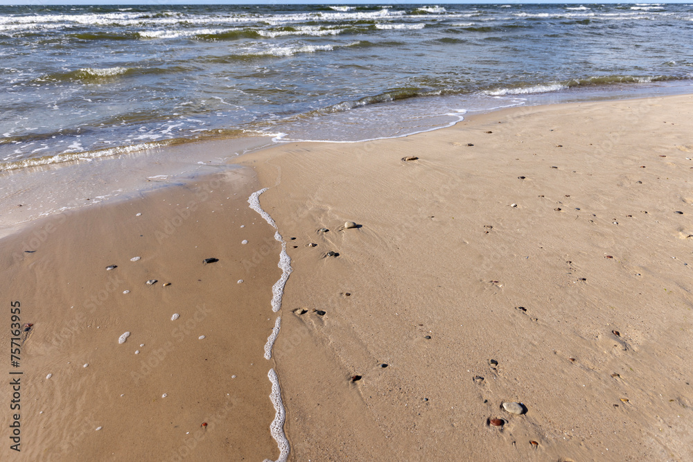 Picturesque view of the sandy beach of the Baltic Sea, foamy water flowing into the sand, Wolin Island, Miedzyzdroje, Poland Picturesque view of the sandy beach of the Baltic Sea, foamy water flowing into the sand, Wolin Island, Miedzyzdroje, Poland