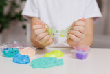 Girl playing with different colors slime at table