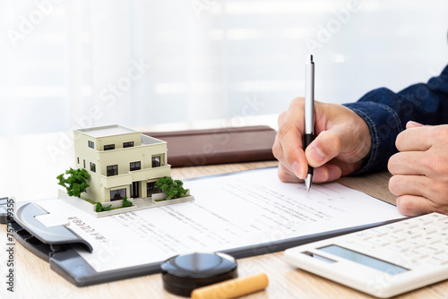 不動産売買の契約書を記入する男性の手