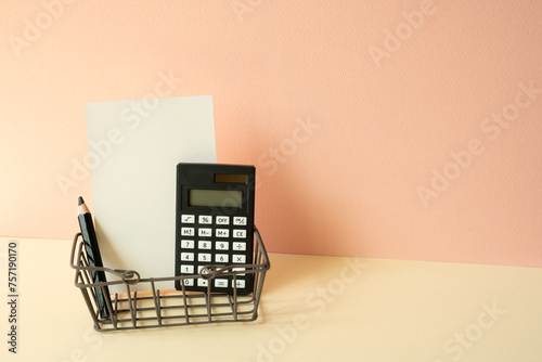 Obraz na płótnie Consumer shopping basket with calculator, pencil, memo pad on ivory and pink background. Economic Concept w salonie