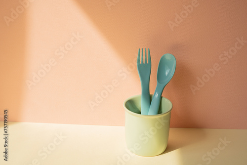 Obraz na płótnie Kitchen blue cutlery fork and spoon in holder on ivory table. pink wall background w salonie